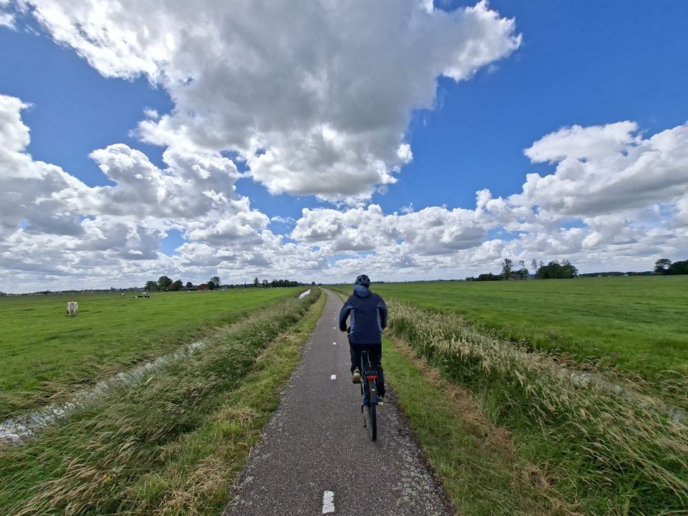 Cycliste sur une piste au milieu des champs néerlandais