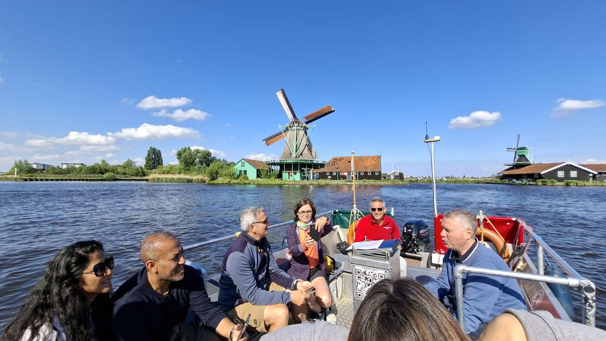 Groupe en bateau devant des moulins